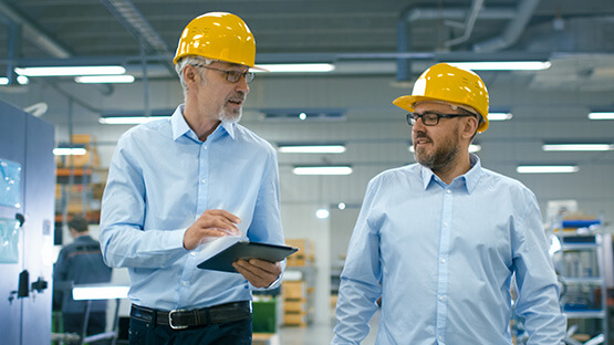 Two factory workers talking and using a tablet